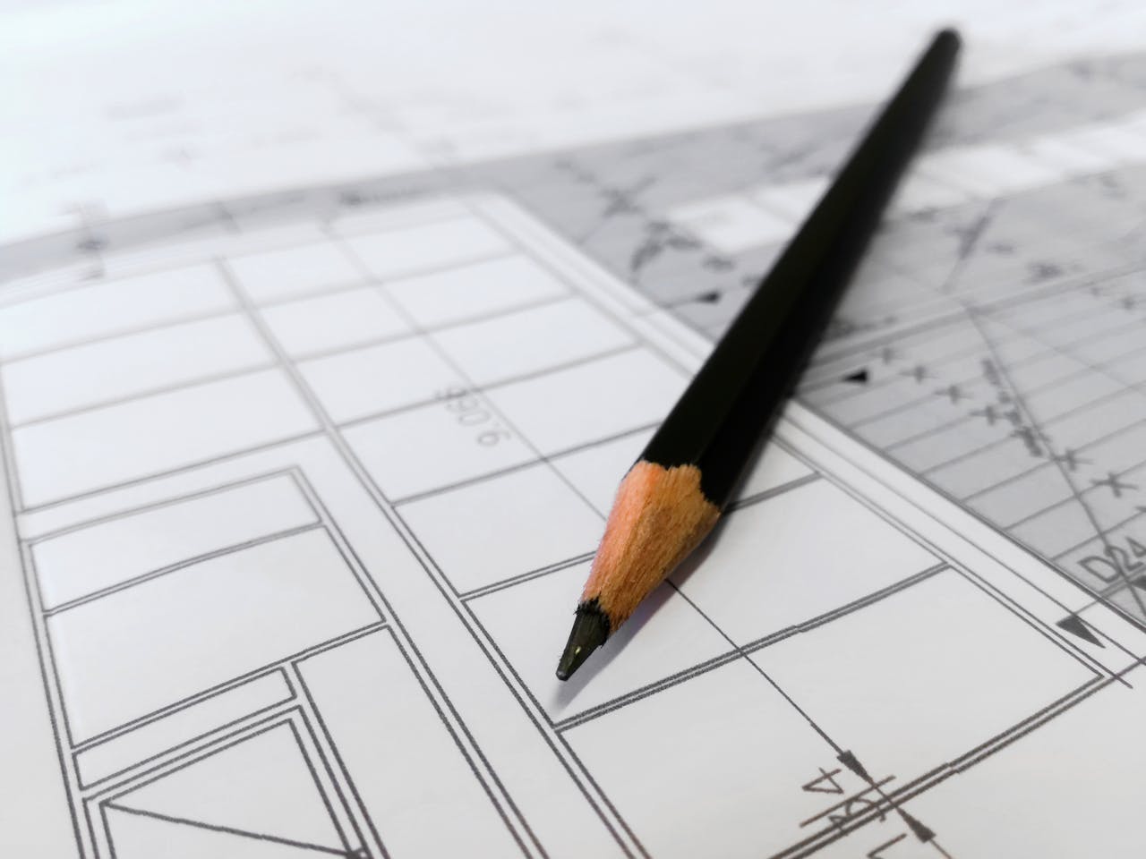 Home Detailed image of a black pencil resting on architectural blueprints, ideal for design and planning themes.